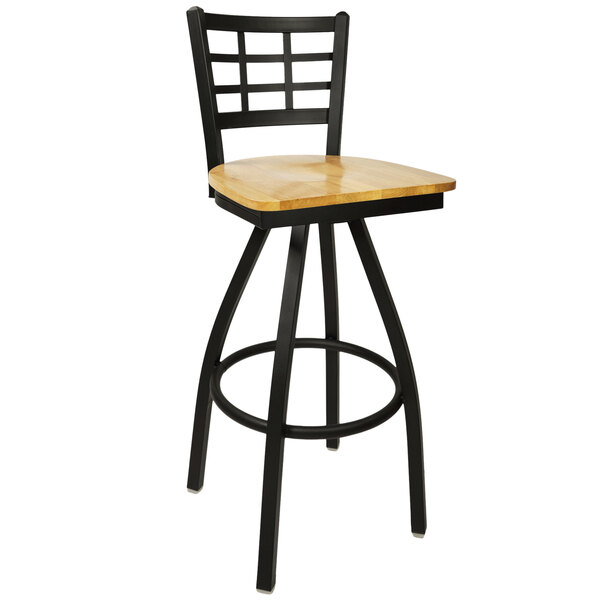 A BFM Seating black metal swivel bar stool with a natural wood seat.