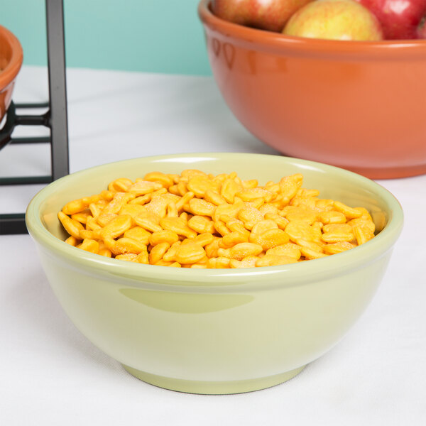 A Cal-Mil sage melamine bowl of cereal and apples on a counter.