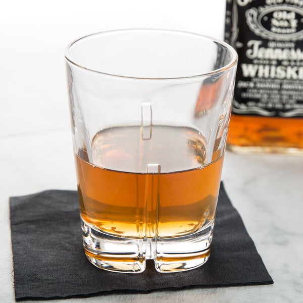 A Spiegelau whiskey glass filled with brown liquid on a napkin.