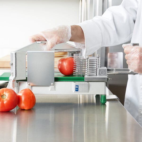 A person in white gloves using a Garde TSLC14 Tomato Slicer to cut a tomato.