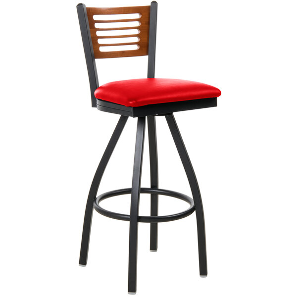 A black metal restaurant bar stool with a cherry wood back and red vinyl swivel seat.