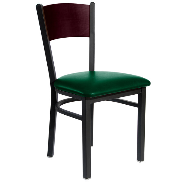 A BFM Seating black metal side chair with a mahogany wooden back and green vinyl seat.
