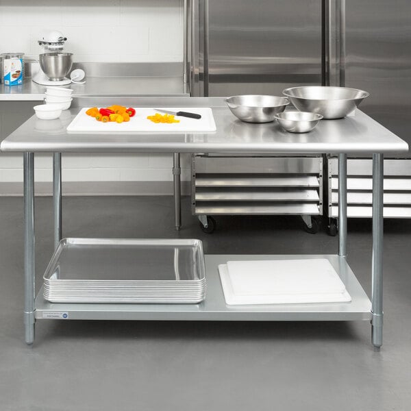 A Steelton stainless steel work table with an undershelf in a professional kitchen with bowls on it.