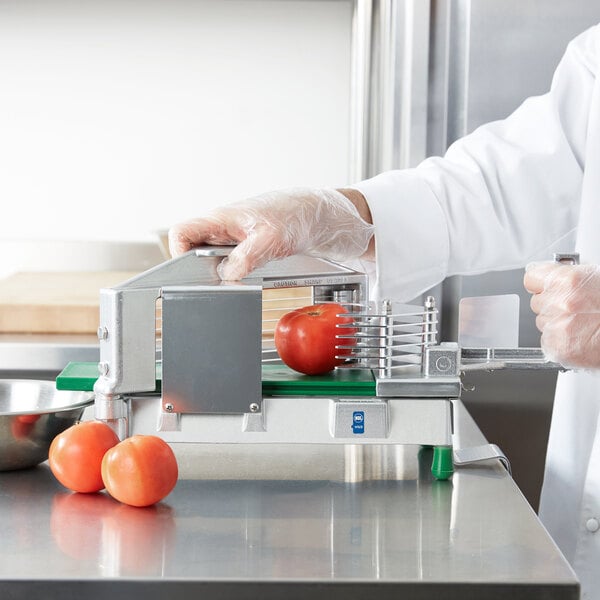 A person in white gloves using a Garde 3/8" Tomato Slicer to cut a tomato.