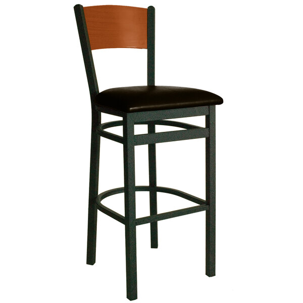 A BFM Seating black metal bar stool with a dark brown vinyl seat and cherry finish wooden back.