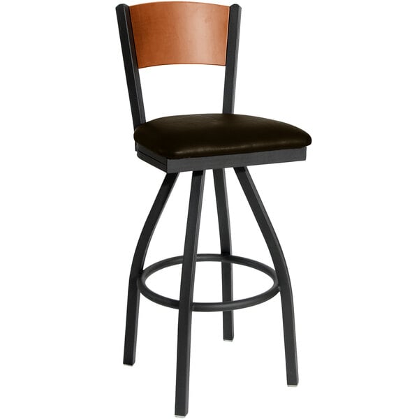 A black metal swivel bar stool with a cherry wood back and dark brown seat.
