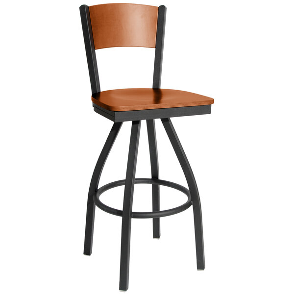 A BFM Seating black metal bar stool with a cherry finish wooden seat and back.