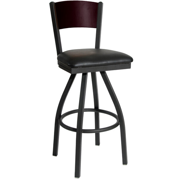 A black metal swivel bar stool with a black vinyl seat and mahogany finished wood back.