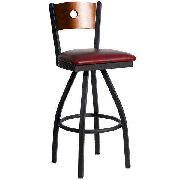 A BFM Seating black metal bar stool with a cherry wood back and red vinyl seat.