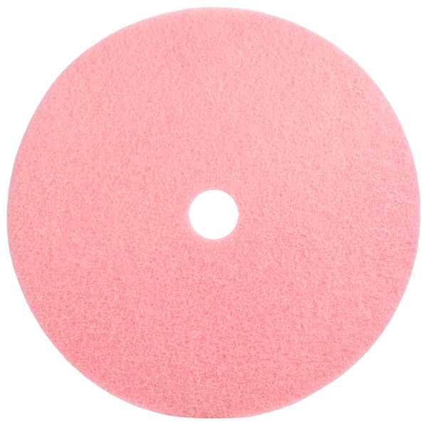 A pink circular Scrubble burnishing pad with a hole in the middle.
