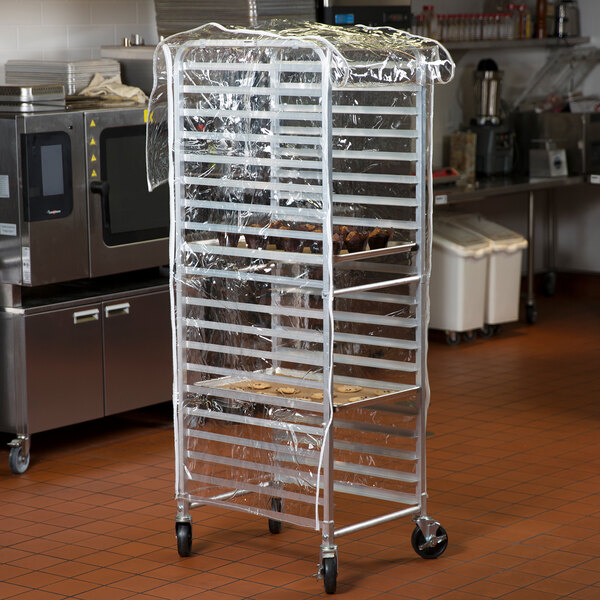 A clear plastic bun pan rack cover fitted over a tall metal rack in a commercial kitchen.