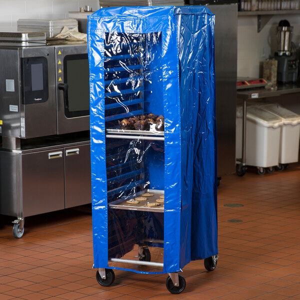 A blue 63-inch vinyl bun pan rack cover protecting a rack of trays in a commercial kitchen.