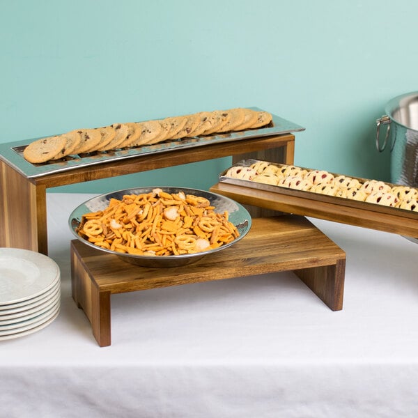 A Tablecraft acacia wood cascade riser set displaying trays of cookies and snacks on a table.