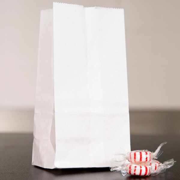 A stack of Duro white paper bags filled with red and white striped candy.