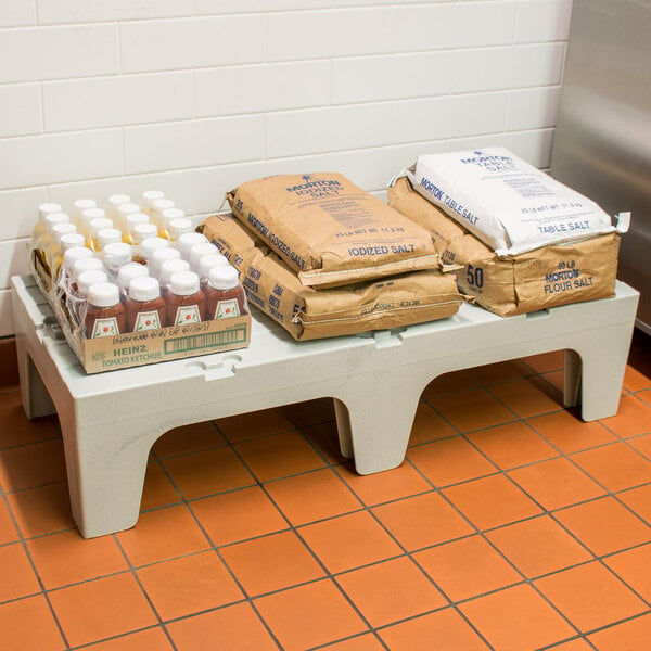 A white Cambro solid top dunnage rack with brown bags and salt packets on it.