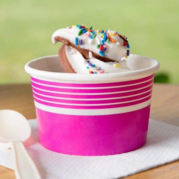 A pink and white striped Choice paper cup filled with ice cream and sprinkles.