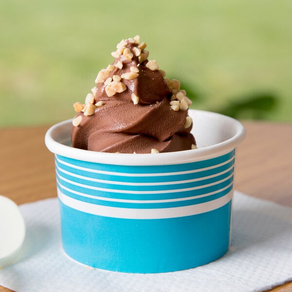 A blue Choice paper cup filled with chocolate ice cream topped with nuts.