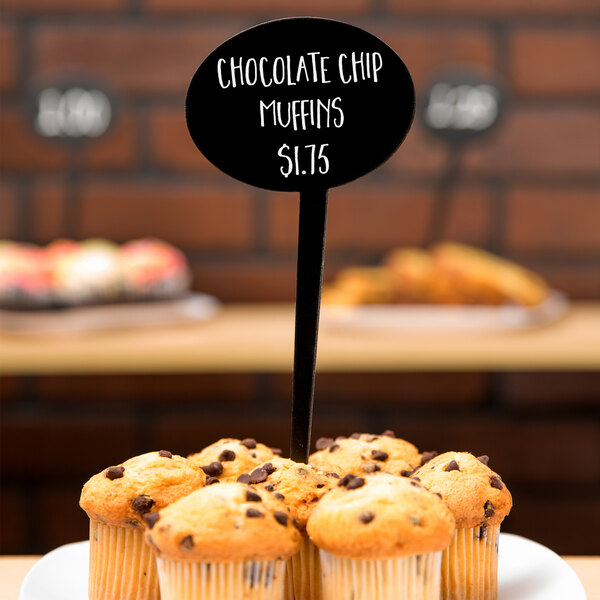 A plate of chocolate chip muffins with American Metalcraft mini oval chalkboard picks on the table.
