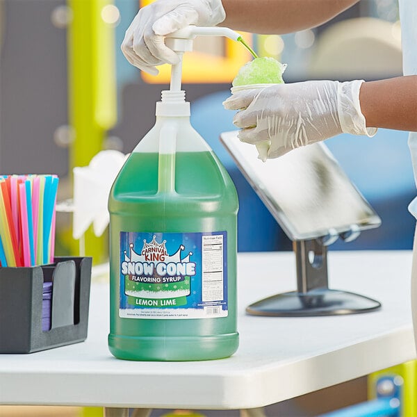A gloved hand pouring Carnival King Lemon Lime syrup into a large container.