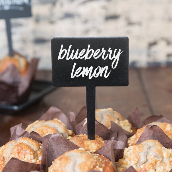 A table with a group of muffins with American Metalcraft mini rectangle chalkboard picks with a sign that says blueberry lemon muffins.