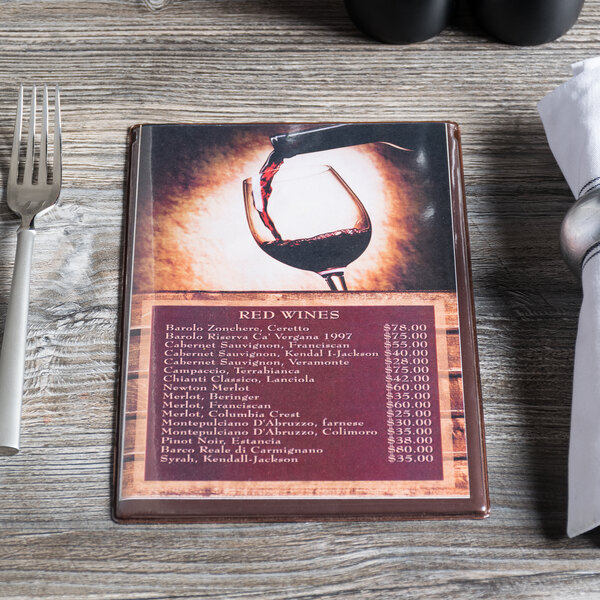 A chocolate menu board on a table with a glass of wine.