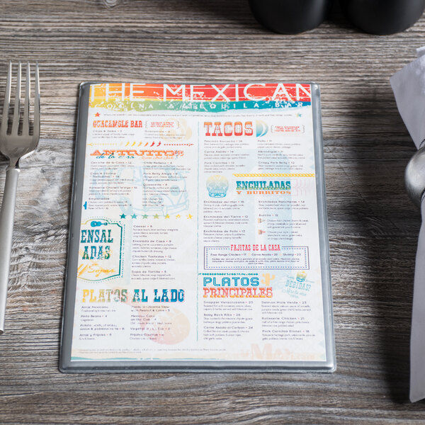 A Menu Solutions silver menu board on a wood table in a Mexican restaurant.