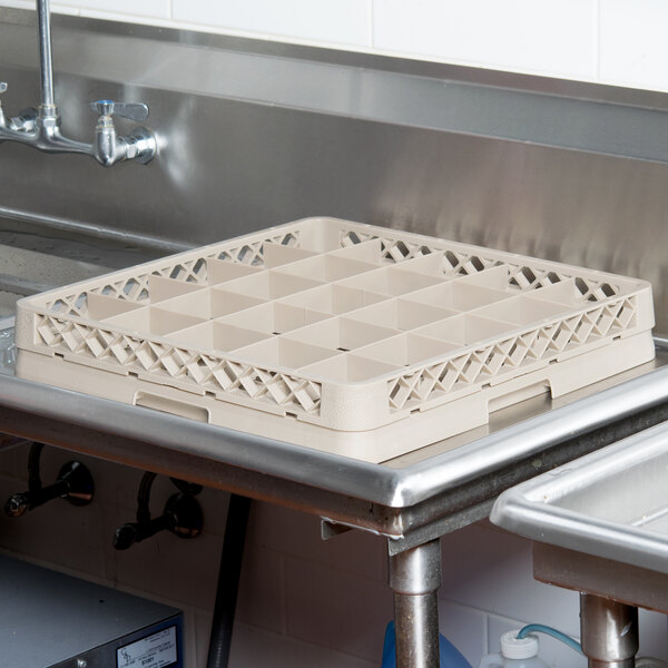 A Vollrath Traex beige plastic dish rack with compartments on a counter.
