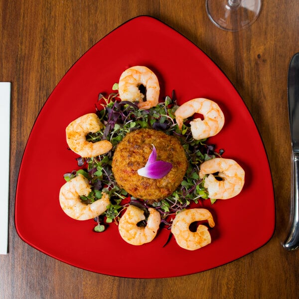 A GET Red Sensation triangular melamine plate with shrimp and vegetables on it.