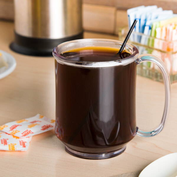 A clear glass GET Tritan mug with a straw on a table.
