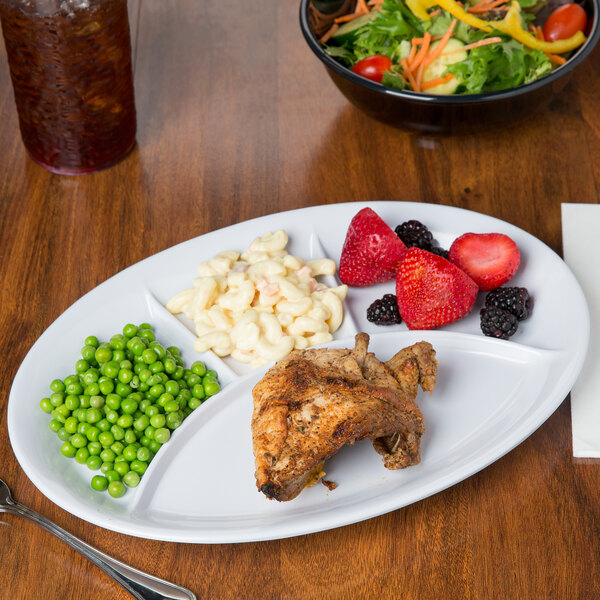 A white melamine platter with compartments holding a chicken breast, peas, and strawberries.