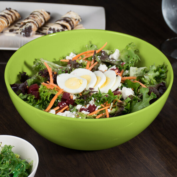 A green BambooServe salad bowl filled with a vegetable salad.