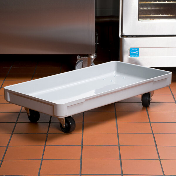 A white MFG Tray fiberglass dough proofing box dolly on a tile floor.