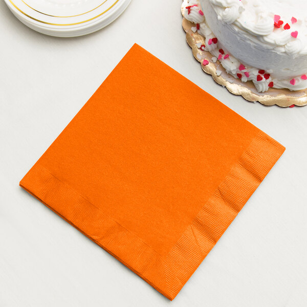 A Sunkissed Orange paper dinner napkin next to a white cake.