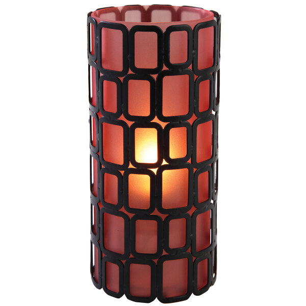 An orange glass candle holder with a lit candle inside.