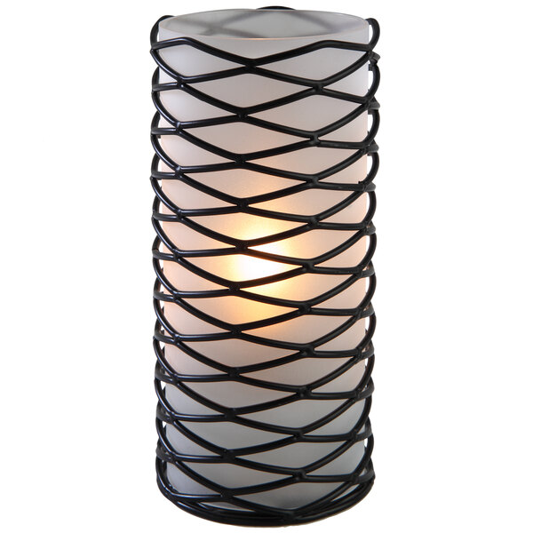 A close-up of a black wire mesh candle holder with a lit candle inside.