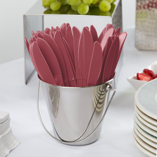 A bucket of burgundy plastic knives.