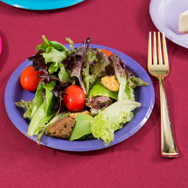 A plate of salad on a purple paper plate with a fork and knife.