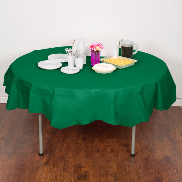 A table with a green Creative Converting octagonal table cover, plates, and cups.