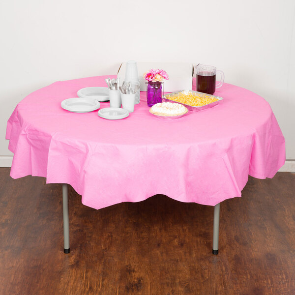 A table with a pink Creative Converting octyround tablecloth, plates, and cups with food on it.