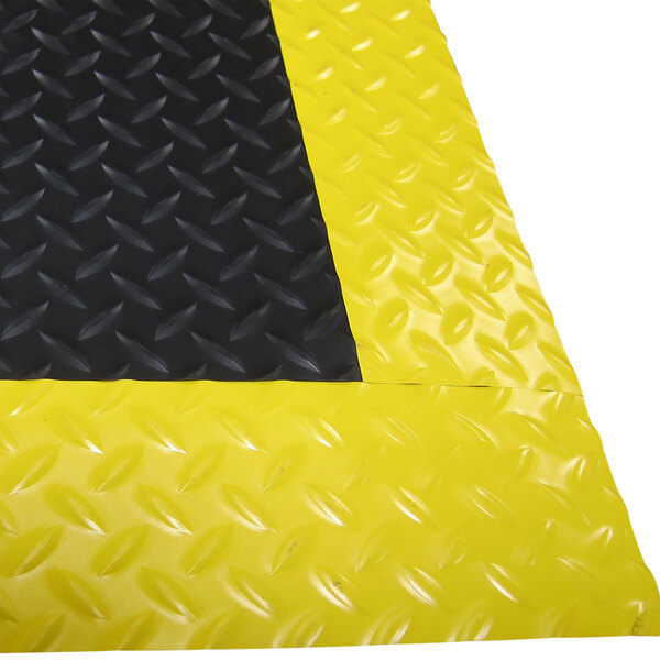 A black Cactus Mat diamond plate anti-fatigue mat with a yellow safety edge.