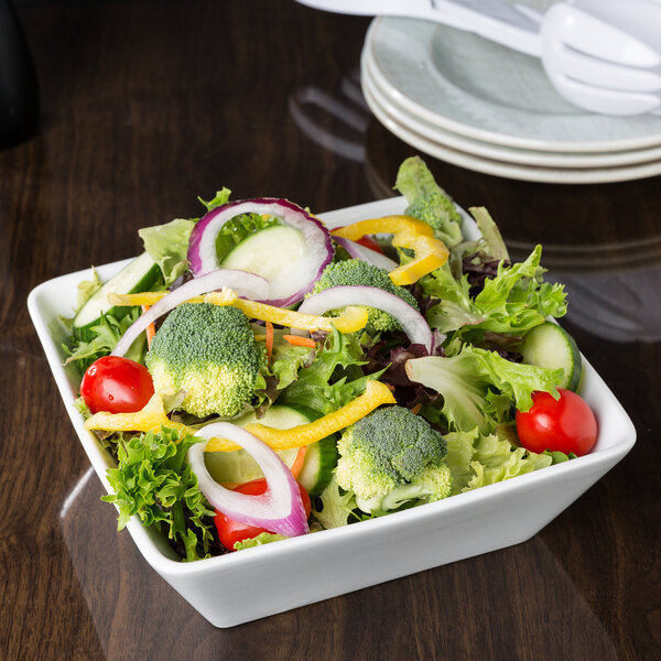 A white Libbey square porcelain bowl filled with a vegetable salad on a counter.