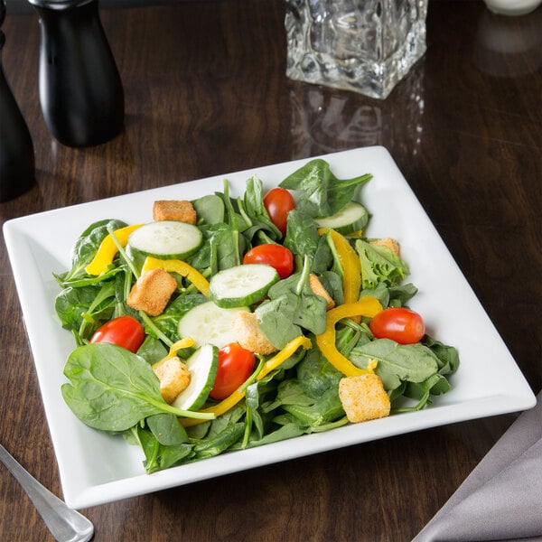 A close up of a vegetable salad in a Libbey Ultra Bright White square pasta bowl.