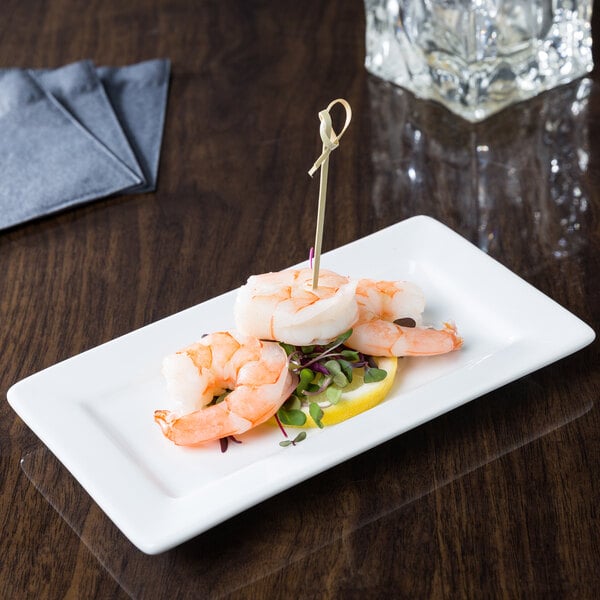 A Libbey white porcelain rectangular plate with shrimp on a table.
