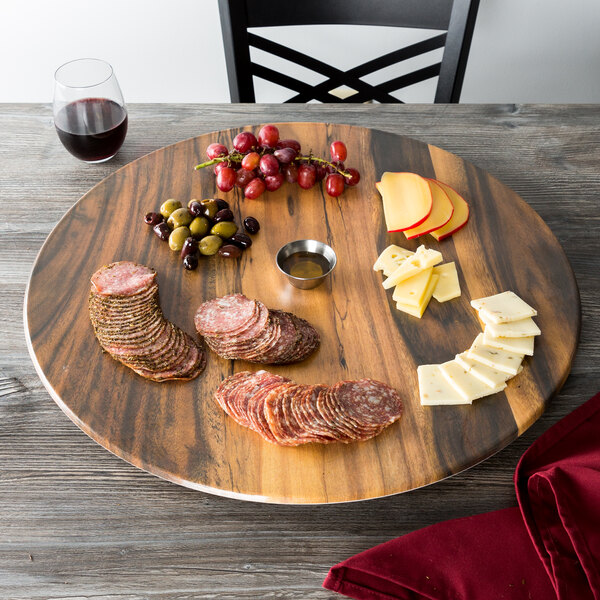 An American Metalcraft faux acacia melamine serving board with cheese, salami, and grapes on a table.