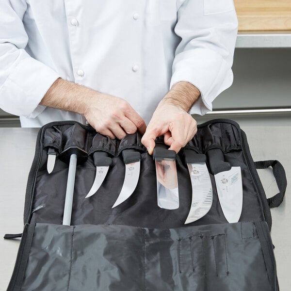 A chef holding a Victorinox knife set in a black bag.