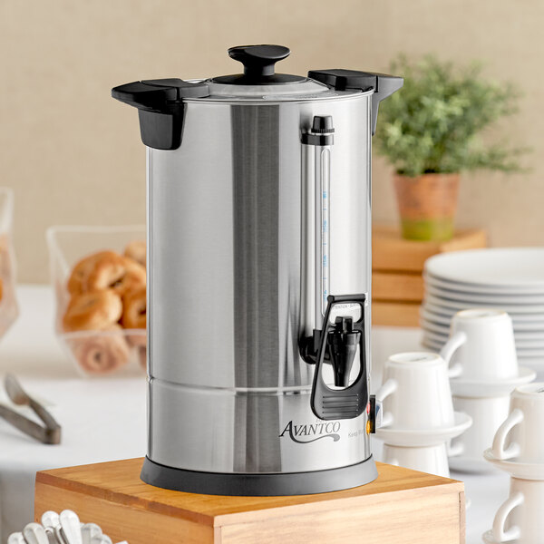 An Avantco stainless steel coffee urn on a table in an outdoor catering setup.