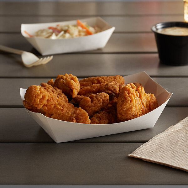 A white paper food tray with fried chicken on a table.