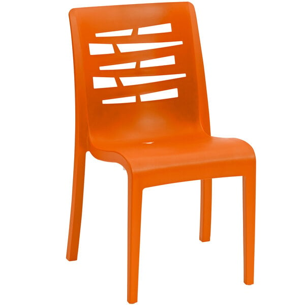 An orange plastic Grosfillex Essenza stacking chair with a cut out design on the back.