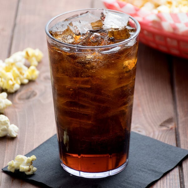 A Cambro clear plastic tumbler filled with soda and ice with a bowl of popcorn.