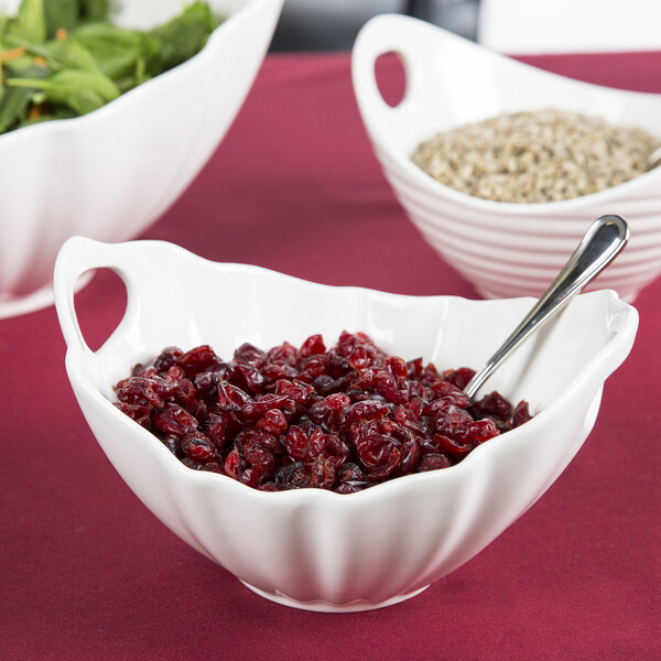 A white porcelain boat bowl with wave texture filled with cranberry sauce and a spoon.